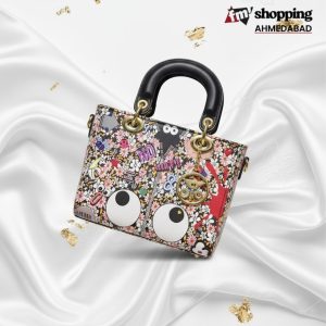 Multicolor cartoon print mini handbag with black top handle, playful graphic design, and gold charm detail.