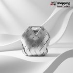 Metallic silver woven handbag with geometric basket-style design and structured triangle top handle.