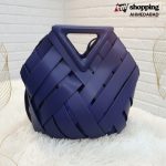 Deep navy blue woven handbag with geometric basket-style design and structured triangle top handle.
