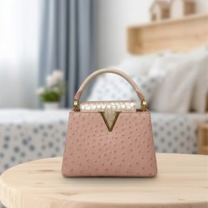 Pink ostrich texture top handle bag with metallic crocodile print 'V' closure.