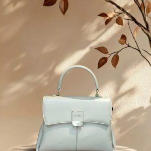 Mint green flap top-handle handbag on wooden table